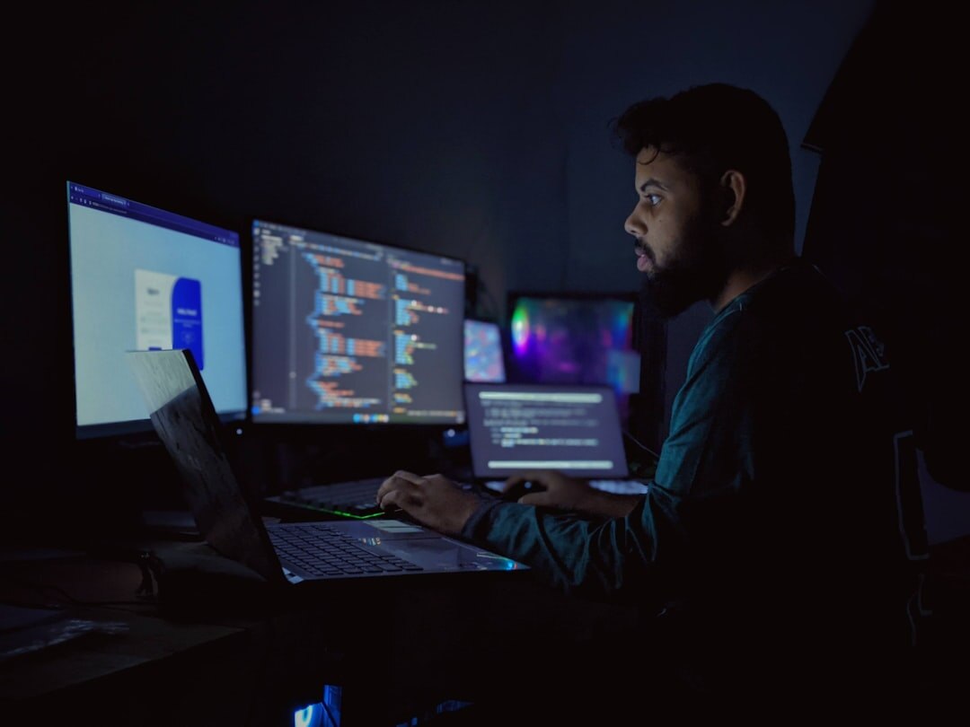Software developer working with multiple screens showing code and application interfaces